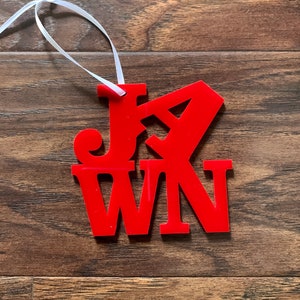 Op de afbeelding: Rode acryl ornament met het woord "JAWN" uitgesneden. De ornament hangt aan een wit lint.