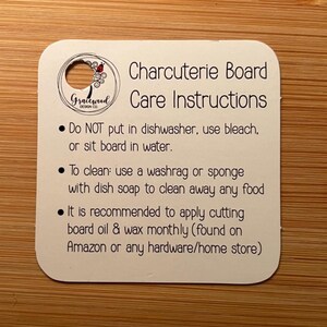 K&ouml;nnte beinhalten: Eine wei&szlig;e Karte mit abgerundeten Ecken, mit dem Text "Charcuterie Board Care Instructions". Die Karte enth&auml;lt Pflegehinweise: Sp&uuml;lmaschine vermeiden, Waschlappen verwenden und monatlich Schneide&ouml;l auftragen. Oben befindet sich ein kleines Loch.