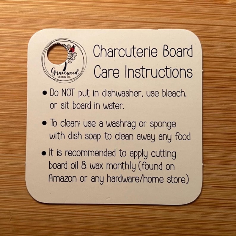K&ouml;nnte beinhalten: Eine wei&szlig;e Karte mit abgerundeten Ecken, mit dem Text "Charcuterie Board Care Instructions". Die Karte enth&auml;lt Pflegehinweise: Sp&uuml;lmaschine vermeiden, Waschlappen verwenden und monatlich Schneide&ouml;l auftragen. Oben befindet sich ein kleines Loch.