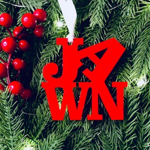 Op de afbeelding: Rood houten ornament met het woord "JOIN" in een gestileerd lettertype. Het ornament hangt aan een groene kerstboom.
