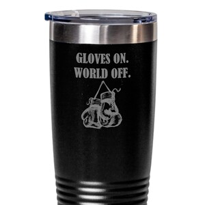 May include: Black stainless steel tumbler with a white inscription that reads "Gloves On. World Off." and a graphic of boxing gloves hanging from a hook.