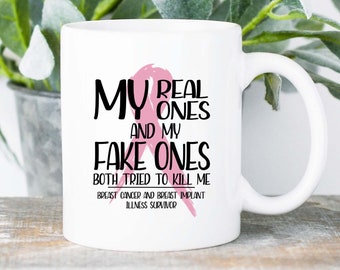 May include: White ceramic mug with the text "MY REAL ONES AND MY FAKE ONES BOTH TRIED TO KILL ME" in black lettering. A pink ribbon graphic is included. The mug also has the text "BREAST CANCER AND BREAST IMPLANT ILLNESS SURVIVOR".