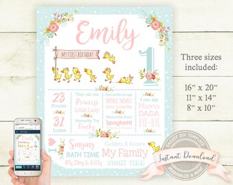 May include: A personalized first birthday sign with a light blue background and floral accents. The sign includes the name "Emily", a number one, and details like weight (23 pounds) and height (31 inches). It also features duckling illustrations and the text "My First Birthday".