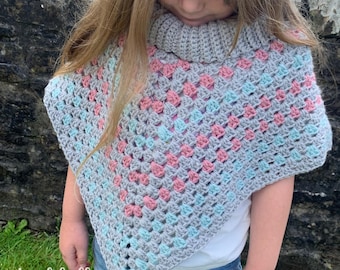May include: A grey, pink and blue crochet poncho with a high neck. The poncho is made with a granny square stitch pattern.