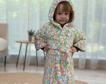 May include: A colourful hooded robe with a tie belt. The robe is made of a soft, fluffy yarn in shades of pink, yellow, green, and white.