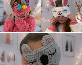 May include: Three crocheted sleep masks with animal designs. The first mask is pink with a unicorn design. The second mask is white with a bunny design. The third mask is grey with a koala design.