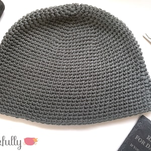 May include: A gray crocheted beanie hat. The hat is made with a textured stitch.