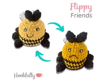 May include: A crocheted bee plush toy with black and yellow stripes. The bee has a white and black bow on its head and a happy face. The bee is reversible and can be flipped to show a sad face.