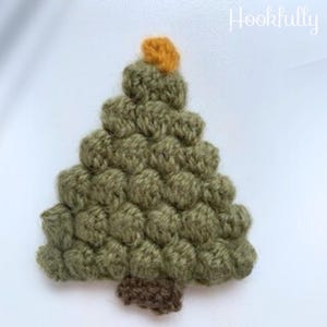 May include: A green crocheted Christmas tree ornament with a brown crocheted trunk and a yellow crocheted star on top.