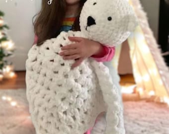 May include: A white crocheted blanket with a white crocheted bear. The blanket is being held by a child.