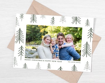 Puede incluir: Una tarjeta de Navidad blanca con un borde verde y blanco de pinos estilizados. La tarjeta presenta una foto de una familia de cuatro personas de pie en un bosque. El texto "Feliz Navidad y Feliz Año Nuevo" está impreso debajo de la foto, y el texto "La familia Smith" está impreso debajo de eso.