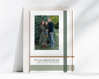 May include: A Christmas card with a photo of a family of three standing in front of a green tree. The card has a green and brown plaid design with the text "Merry Christmas with love, The Jordans".