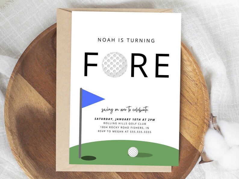 May include: A white card with black text that reads "Noah is turning FORE" with a golf ball graphic. The card is on a brown wooden surface with a blue and green golf course graphic at the bottom. The text below the graphic reads "swing on over to celebrate Saturday, January 10th at 2PM Rolling Hills Golf Club 1804 Rocky Road Fishers, IN RSVP to Megan at 555.555.5555"