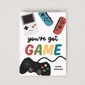 May include: White card with a gaming theme. It features a retro handheld console, two game controllers, and the words "you've got GAME" in colorful letters. The text "FROM: HUDSON" is also included.
