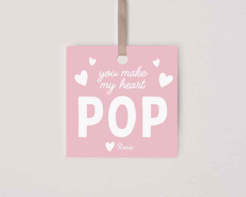 May include: Pink square card with white text that reads "You make my heart POP" with a small heart and the name "Rosie" at the bottom.