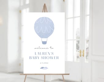 May include: A white welcome sign with a blue hot air balloon graphic and the text "Welcome to Lauren's Baby Shower 6.15.2022".