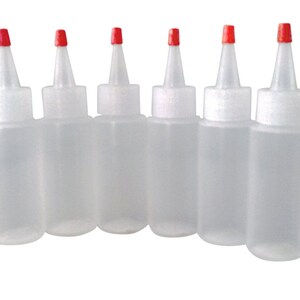 May include: Six clear plastic squeeze bottles with red caps. The bottles are empty and have a narrow opening.