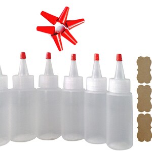 May include: Six clear plastic squeeze bottles with red caps and six red caps. The bottles are arranged in a row. There are six brown paper tags with scalloped edges.