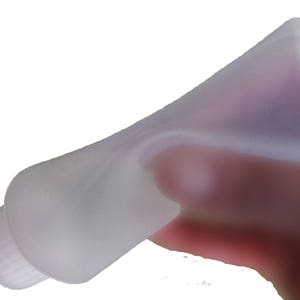 May include: A clear plastic squeeze bottle with a long, thin nozzle. The bottle is designed for dispensing liquids.