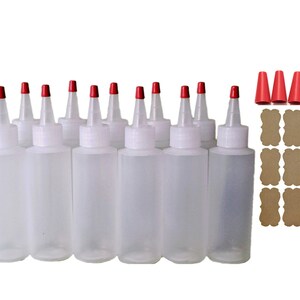 May include: Twelve clear plastic squeeze bottles with red caps and twelve brown paper labels. The bottles are arranged in three rows of four.