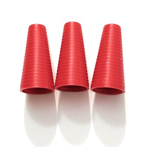 May include: Three red plastic cones with a ribbed texture. The cones are arranged in a row from left to right.