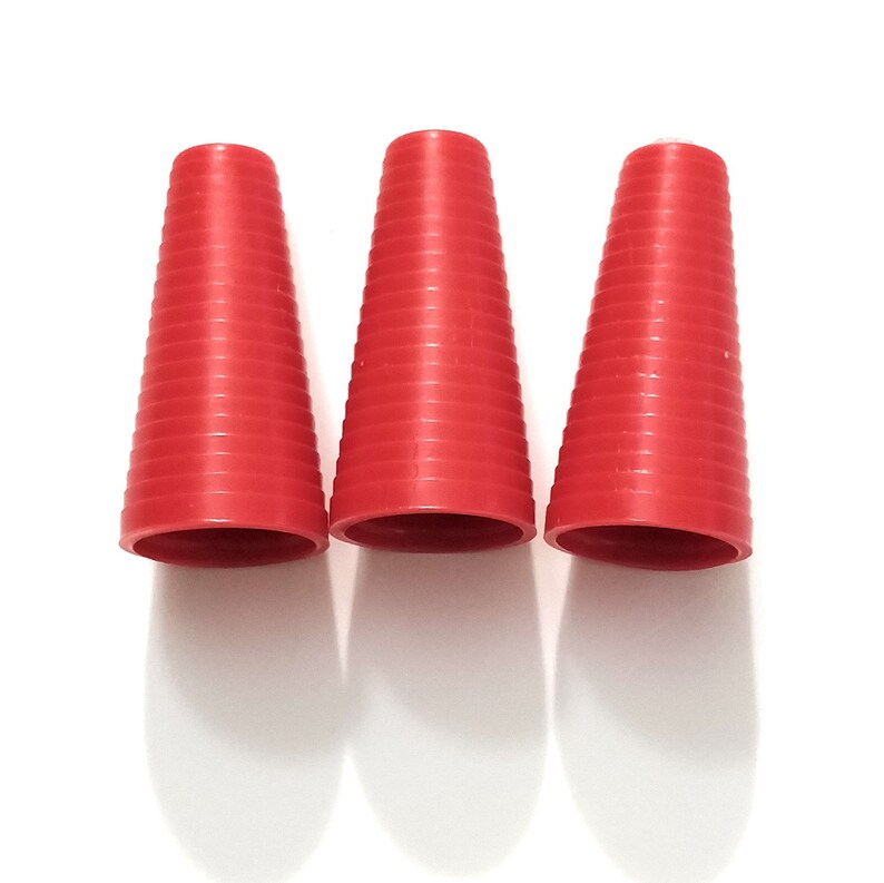 May include: Three red plastic cones with a ribbed texture. The cones are arranged in a row from left to right.