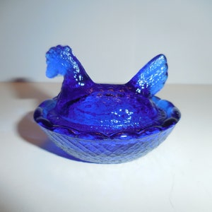 May include: A cobalt blue glass hen and nest dish. The hen is sitting in a nest with a ruffled edge.
