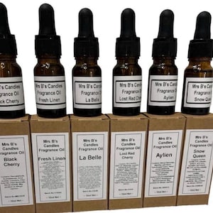 May include: Six amber glass bottles of Mrs B's Candles Fragrance Oil with black droppers, each on a matching box. Scents include Black Cherry, Fresh Linen, La Belle, Lost Red Cherry, Aylien, and Snow Queen. The boxes display the fragrance names.