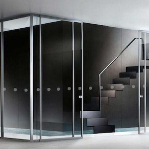 May include: A set of sliding glass doors with a frosted glass panel and a silver frame. The doors open to a room with a staircase and a black tiled floor.