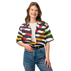 May include: A short-sleeved button-up shirt with a vibrant geometric pattern of black, white, red, pink, orange, yellow, and green stripes. The shirt is worn with a white t-shirt and blue jeans. A black belt with a silver buckle is visible.