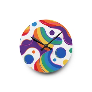 May include: Round wall clock with a white face featuring a colorful, abstract design of rainbow-colored shapes and blue and purple circles. The clock has black hands and a black clock mechanism.