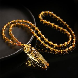Wonderful Deco style carved cognac coloured glass cicada pendant necklace 24"