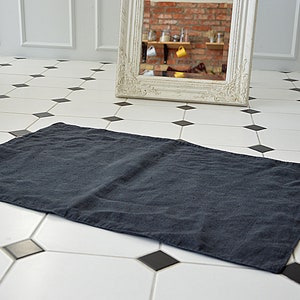 Può includere: Un tovaglietta di lino grigio scuro su un pavimento di piastrelle bianche e nere.