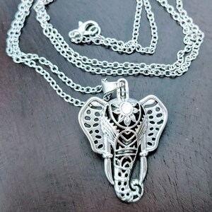 May include: A silver chain necklace with an ornate silver elephant pendant. The elephant has a detailed design with a flower on its head.