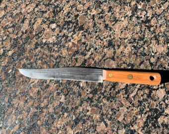 May include: A stainless steel kitchen knife with a wooden handle. The handle has three brass rivets and the text "KC" is engraved on the handle.