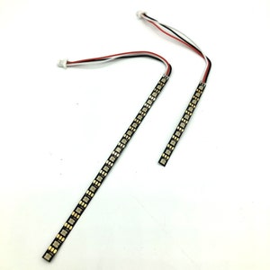 Puede incluir: Dos tiras de luz LED negras con conectores dorados y cables rojos y blancos. Cada tira tiene 16 LED.