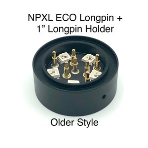 Puede incluir: Un soporte de longpin de pl&aacute;stico negro con longpins de color dorado. El soporte tiene una base circular y una parte superior cil&iacute;ndrica. El texto "NPXL ECO Longpin + 1" Longpin Holder" est&aacute; impreso en la parte superior del soporte. El texto "Older Style" est&aacute; impreso debajo del soporte.