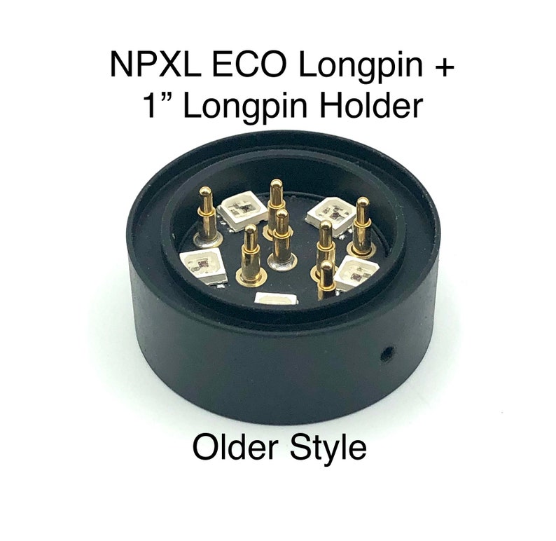 Puede incluir: Un soporte de longpin de pl&aacute;stico negro con longpins de color dorado. El soporte tiene una base circular y una parte superior cil&iacute;ndrica. El texto "NPXL ECO Longpin + 1" Longpin Holder" est&aacute; impreso en la parte superior del soporte. El texto "Older Style" est&aacute; impreso debajo del soporte.