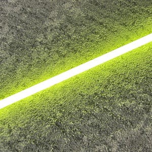 Puede incluir: Un sable de luz amarillo brillante con una empuñadura plateada. La hoja emite una luz brillante y uniforme, lo que sugiere una poderosa fuente de energía. El sable de luz se encuentra sobre un fondo gris texturizado.