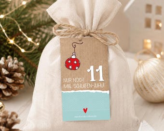 May include: A beige fabric drawstring pouch tied with twine, featuring a rectangular brown tag. The tag displays a red Christmas ornament, the number 11, and the German text 'NUR NOCH MAL SCHLAFEN-JUHUI' above a light blue section with a small red heart.