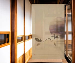 以下が含まれることがあります： ベージュ色の日本の間仕切り。黒インクの花柄のデザイン。アートワークは大きな紫色の円と、葉と花のある繊細な枝が特徴です。仕切りは木製のフレームに吊り下げられており、穏やかでミニマリストな美学を作り出しています。