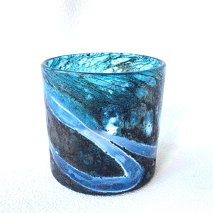 May include: A teal blue glass candle holder with a swirling, marbled pattern in shades of blue, black, and white.