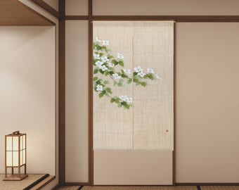 May include: A beige linen room divider with a white floral design. The divider is hanging in a room with a wooden floor and a wooden door.