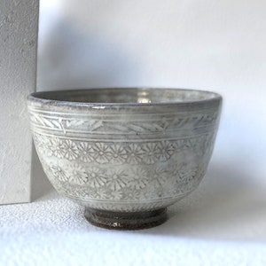 May include: A white ceramic bowl with a floral design. The bowl has a slightly flared rim and a small foot.