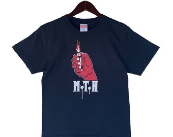 May include: A navy blue t-shirt with a graphic of a red hand holding a lit match. The text "M.T.H." is printed below the graphic.