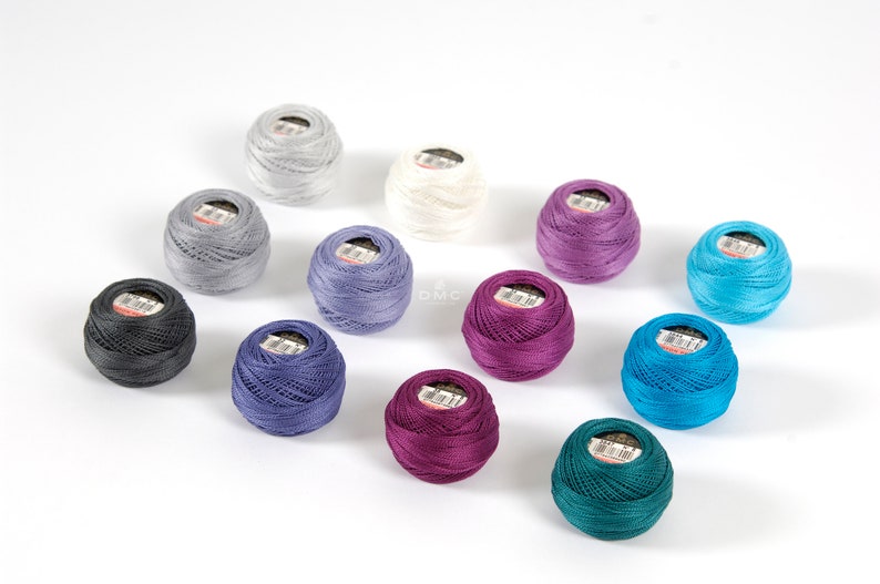 May include: Assortment of 12 spools of DMC embroidery floss in various colors, including teal, purple, blue, gray, and white.