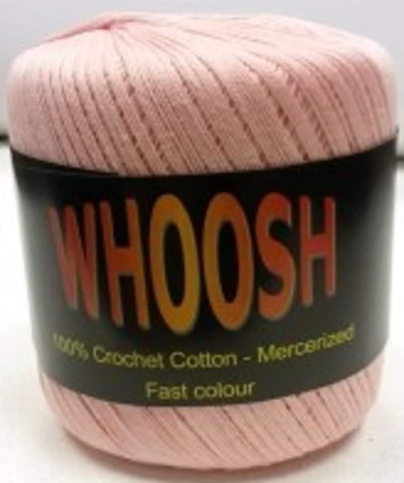 K&ouml;nnte beinhalten: Eine rosa Garnrolle mit dem Wort "WHOOSH" in orangefarbenen Buchstaben auf einem schwarzen Etikett. Das Etikett tr&auml;gt au&szlig;erdem die Aufschrift "100% H&auml;kelgarn - Mercerisiert Schnelle Farbe".