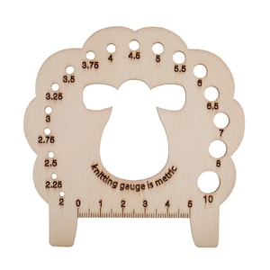 May include: A wooden knitting gauge shaped like a sheep, with holes for needle sizes from 2 to 10. A ruler is along the bottom. The text "knitting gauge is metric" is printed on the gauge. Metric measurements are used.