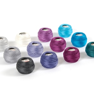 May include: Assortment of 12 spools of embroidery floss in various colors, including teal, purple, gray, and white.