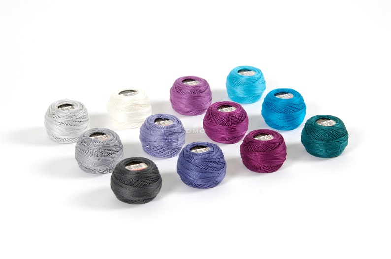 May include: Assortment of 12 spools of embroidery floss in various colors, including teal, purple, gray, and white.